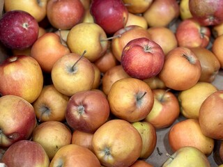 A mound of large red yellow coloured apples in boxes is displayed in the window of the supermarket's vegetable stand, demonstrating organic, vegetarian and healthy food. Close-up