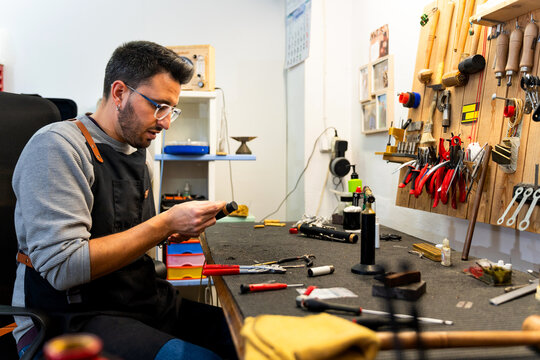 Luthier carefully examining musical instrument part in workshop