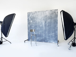 Professional photography studio setup with softbox lights, a textured backdrop, and a metal chair. Ideal for portrait  photography.
