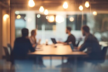 blurred photo of an office meeting room with business people sitting around the table with laptops and documents, discussing business plans, talking and working together