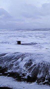 Solitary structure on reynisfjara black sand beach enduring icelands powerful waves