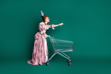 Aristocratic woman in vintage dress pushing a modern shopping cart against a green background