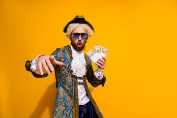 Young Man in Historical Noble Costume Posing with Modern Cash Against Yellow Background