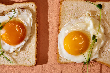 four toasts with a frosted egg with microgreens on a pink background