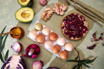 the process of coloring farm eggs for Easter with natural dyes, top view on a green background