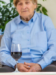 Old woman drinking wine. Selective focus.