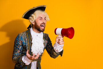 Man dressed as 18th century nobleman shouting through megaphone against yellow background