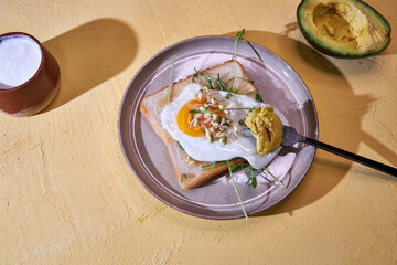 breakfast scrambled eggs with toasted bread with herbs and avocado on a ceramic plate top view