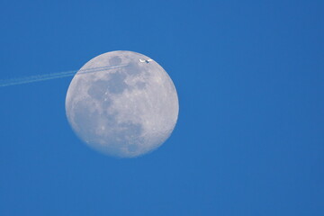 Plane commercial jet flies past a full moon. 