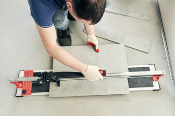 A machine for cutting large ceramic tiles into smaller tiles with precise dimensions. Close-up of...