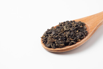 large wooden spoon on a white background. Green leaf tea is poured into a spoon. Tea party concept. Traditional Indian drink