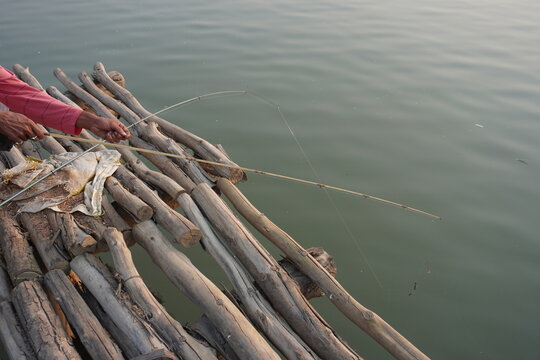 A person on a bamboo raft engaged in fishing or simply navigating a waterway
