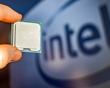 Intel processor, hand holding an Intel CPU, with the company logo in the background.