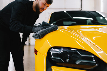 Cleaner worker dry body car using microfiber after washing automobile. Hand car drying with...