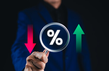 Financial interest rate and market trends concept. Businessman holding magnifying glass with percentage symbol, with red and green arrows, financial market fluctuation, interest rates, economic trend,