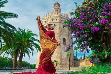 Mujer típica española bailando flamenco con una torre medieval y el cielo a su espalda. Desde la ciudad de Sevilla, Andalucía, España, Europa.  © Juan Pedro Peña