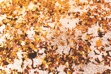 Shiny golden confetti and glitter scattered on a beige background. Festive texture.