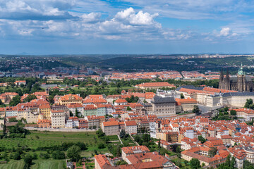 Obraz premium Panoramic view of Prague with the Vltava River, historic bridges, and red rooftops, surrounded by lush greenery. Stunning European cityscape showcasing Czech Republic’s architectural and natural beaut