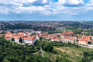 Obraz premium Panoramic view of Prague with the Vltava River, historic bridges, and red rooftops, surrounded by lush greenery. Stunning European cityscape showcasing Czech Republic’s architectural and natural beaut