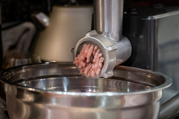 Electric meat grinder. Kitchen tool to mince meat. Meat grinding, preparing food ingredients. Modern meat grinder products on  table in kitchen. The process of cooking minced using an grinder. 