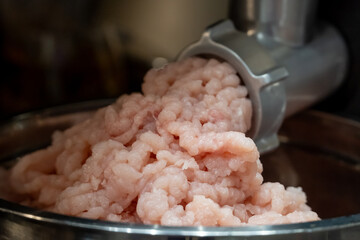 Electric meat grinder. Kitchen tool to mince meat. Meat grinding, preparing food ingredients. Modern meat grinder products on  table in kitchen. The process of cooking minced using an grinder. 