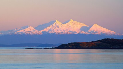 Majestic snow capped mountains reflecting sunrise glow over tranquil sea