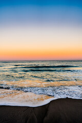 waves crashing on beach with sunset