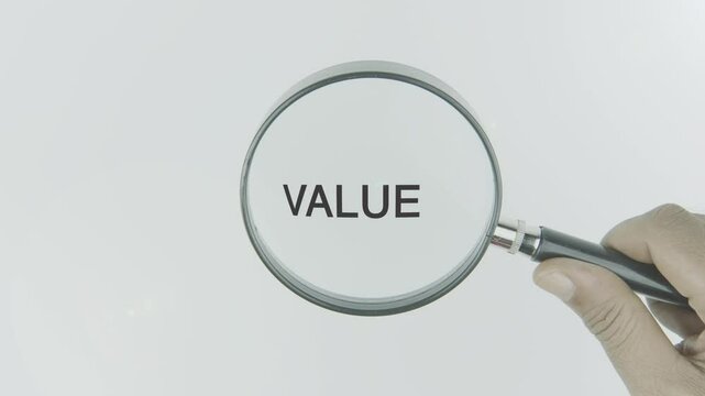 Value text or word highlighted by a magnifying glass in a hand on a white background, symbolizing worth, importance, and significance in decision-making and actions