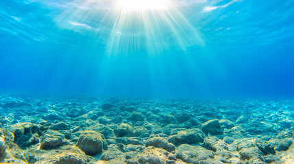 Obraz premium Sunlight penetrating crystal waters casting luminous patterns across rocky underwater landscape, highlighting marine environment's ethereal beauty