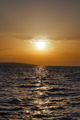 Pastel color sunset above wavy surface of blue sea