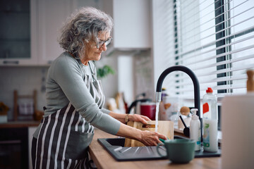 Senior woman washing dishes in the kitchen.