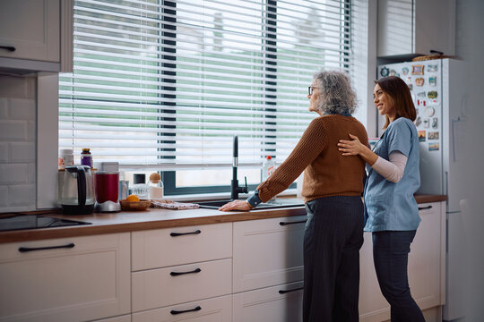 Caring nurse comforting pensive senior woman during her home visit.