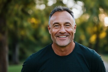 Man with a big smile on his face is standing in a park