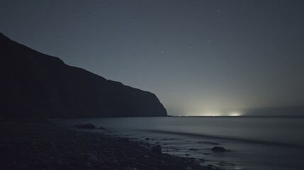 Tranquil seascape with dark coastline under starry night sky