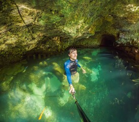 Man tourist in the water of a Mexican cenote surrounded by natural beauty. Adventure travel,...