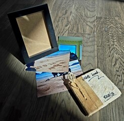 Bathed in gentle sunlight, a framed photograph rests beside a vintage-style notebook and a quaint wooden jewelry box, evoking a sense of timeless warmth and sentimental elegance.