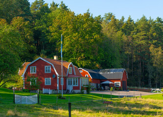 Red and white traditional house by a forest.