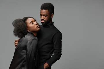 A beautiful couple embraces with emotions, showcasing love and connection against a minimalist gray background, highlighting intimate moments, modern fashion, and diversity