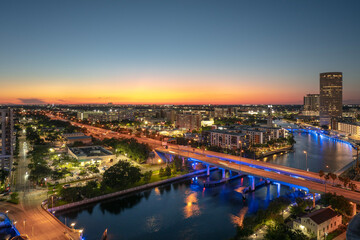 Fototapeta premium American city skyline of Tampa in Florida. Brightly illuminated commercial buildings and highway bridge over Hillsborough river. Night urban landscape of downtown district in USA.