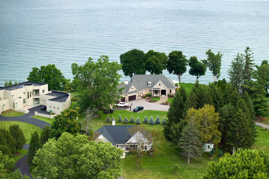 Private residential houses in lakeside suburban sprawl area in Rochester, New York. Upscale suburban homes with large backyard and green grassy lawn in summer season