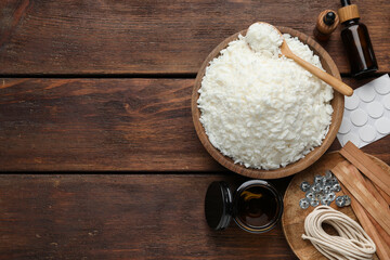 Soy wax and other supplies for making candles on wooden table, flat lay. Space for text
