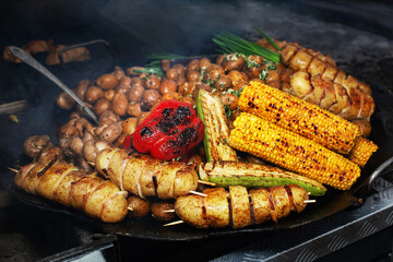 Varied assortment of hot ready-made dishes cooked on the grill. Selling food products at a street fair. Street food to go. Fast food.