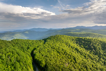 Obraz premium Winding mountain road in summer woods. Appalachian mountains in North Carolina with fresh green forest trees in summertime season. Beauty of USA nature
