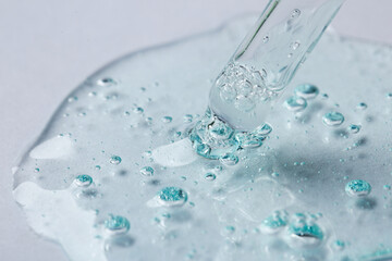 Pipette with cosmetic serum on light background, closeup