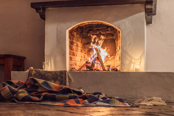 A warm and inviting scene featuring a lit fireplace with glowing firewood and candles. A colorful...