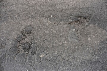 Close up view of cracked and damaged asphalt road surface, highlighting the need for road maintenance and repair