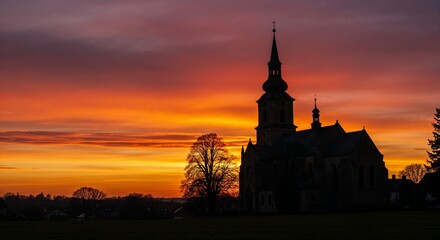 Fototapeta premium Church silhouette against vibrant orange sunset sky for religious websites, spiritual content, travel blogs, inspirational quotes and contemplative visual projects