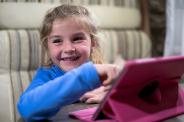 Smiling girl using pink tablet at home