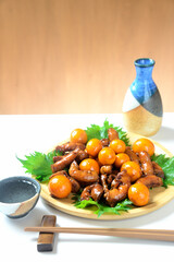 木製プレートに鶏モツ煮込み料理を盛り付けと日本酒