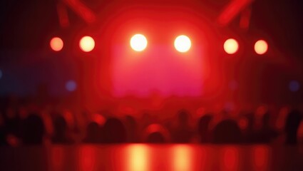 An abstract, blurred image showcasing the vibrant, colorful lights of a concert or stage setting. The soft focus produces a dreamy, atmospheric effect with shades of red, orange, and purple merging.